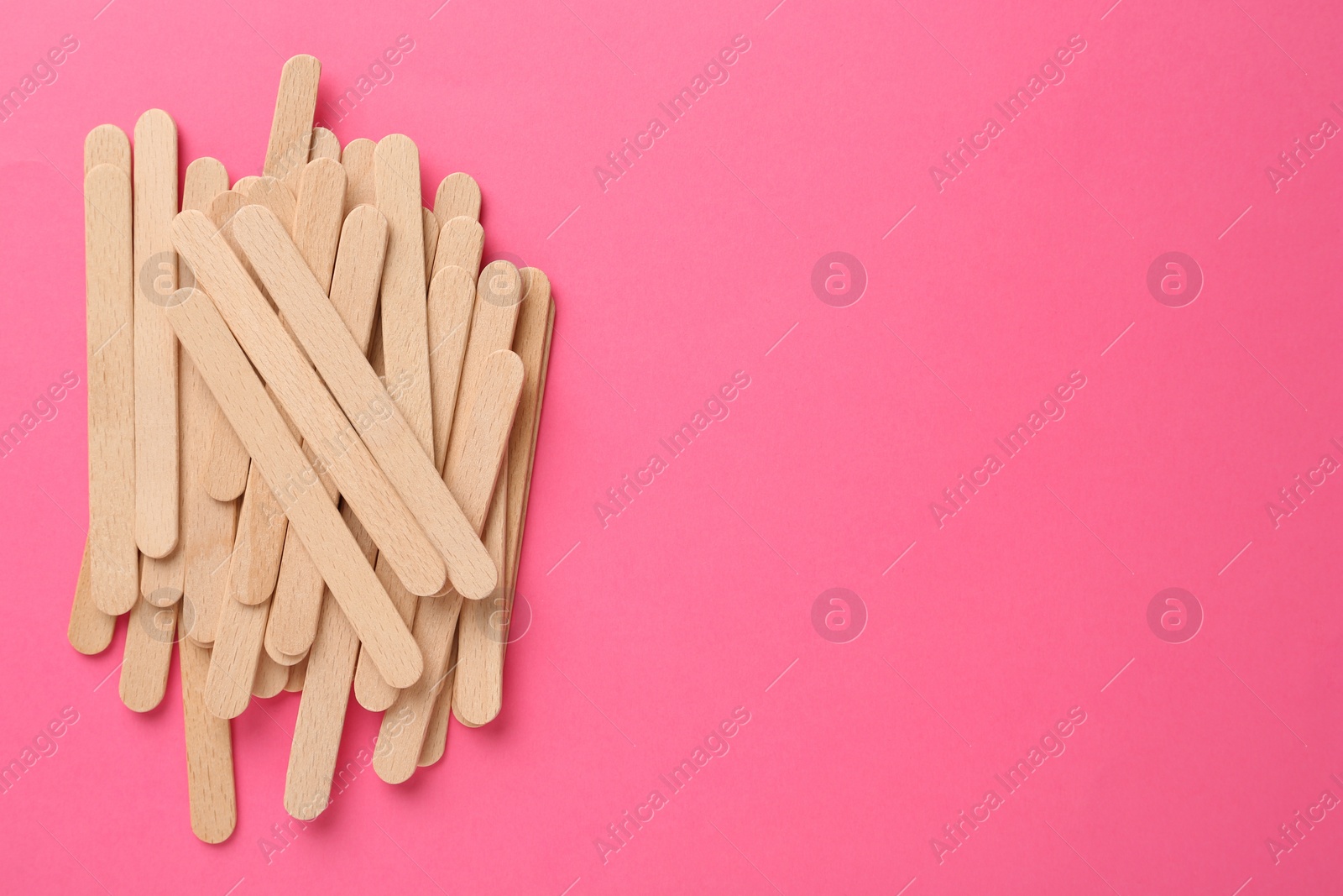 Photo of Wooden waxing spatulas on bright pink background, flat lay. Space for text