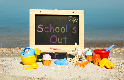 Image of Chalkboard with text SCHOOL'S OUT and toys on beach