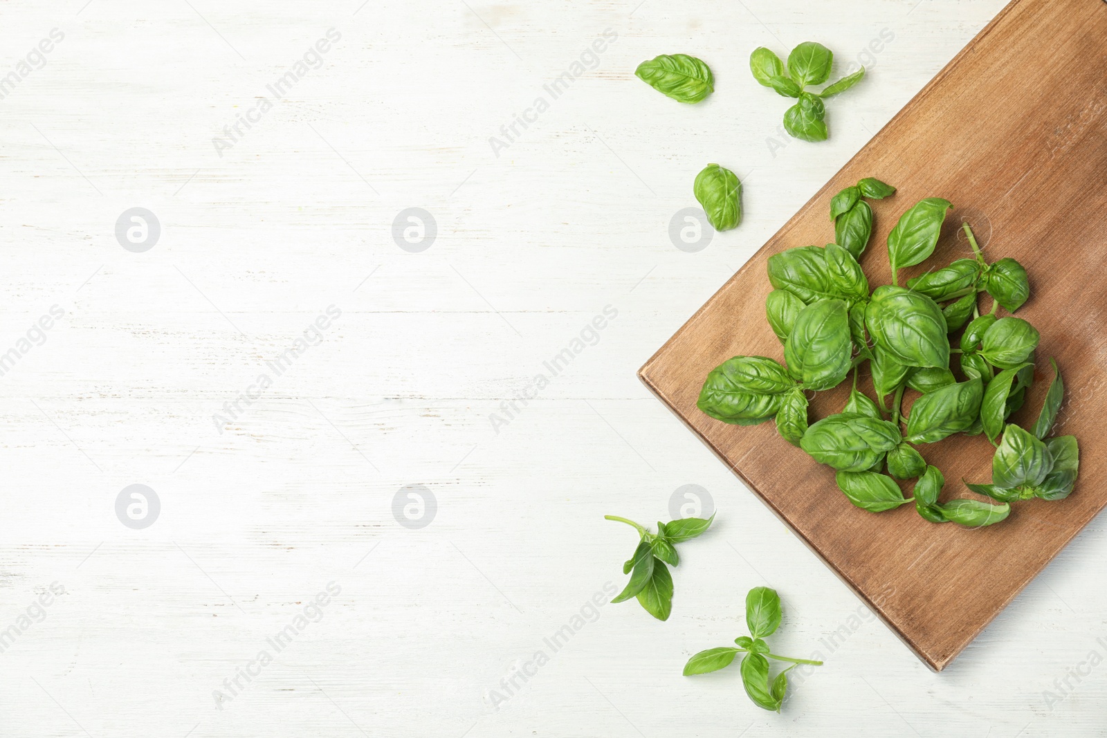 Photo of Board with fresh basil on wooden background, top view. Space for text