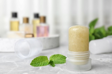 Natural crystal alum deodorant and mint on light grey marble table. Space for text