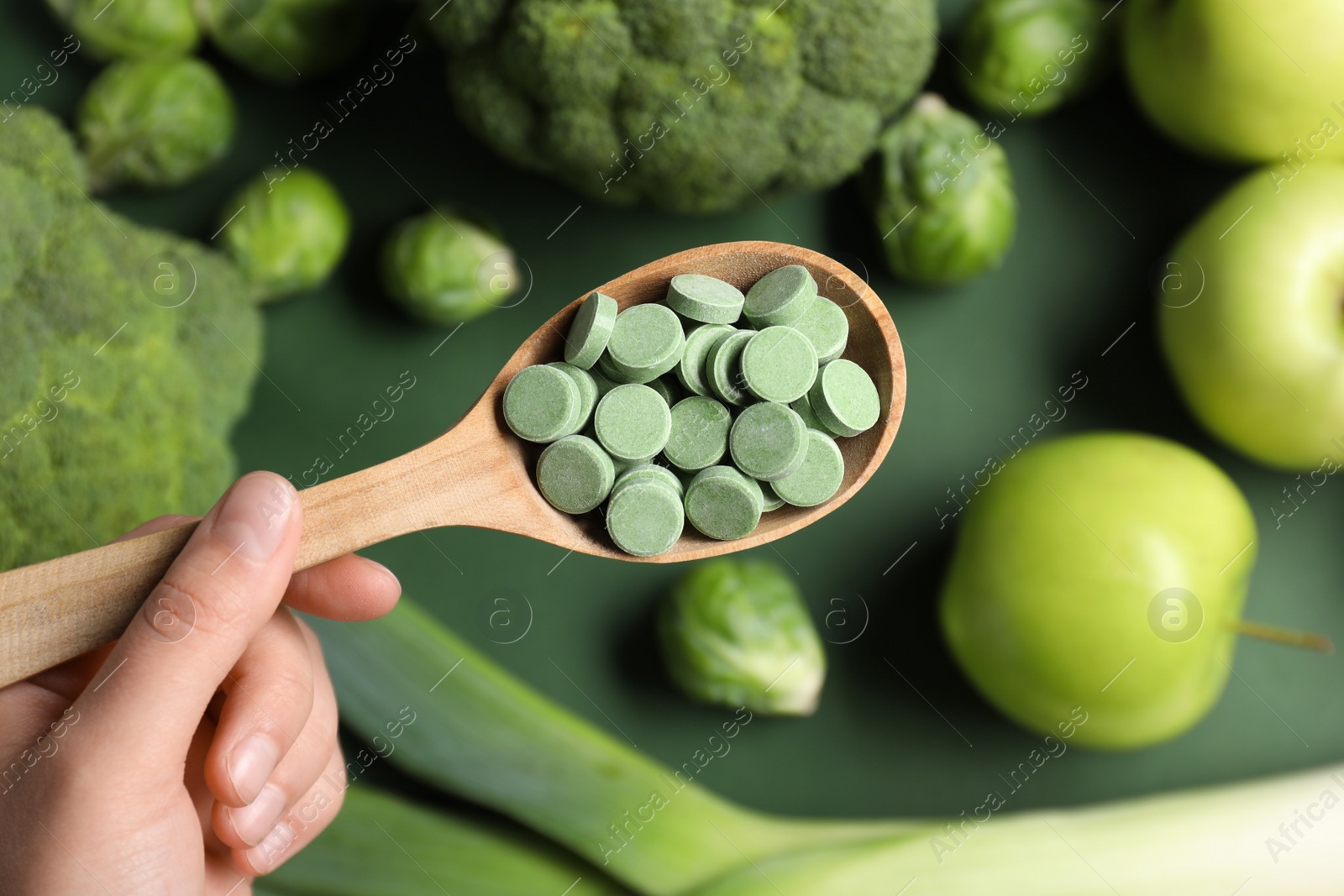 Photo of Woman holding spoon of pills on blurred background, top view. Prebiotic supplements