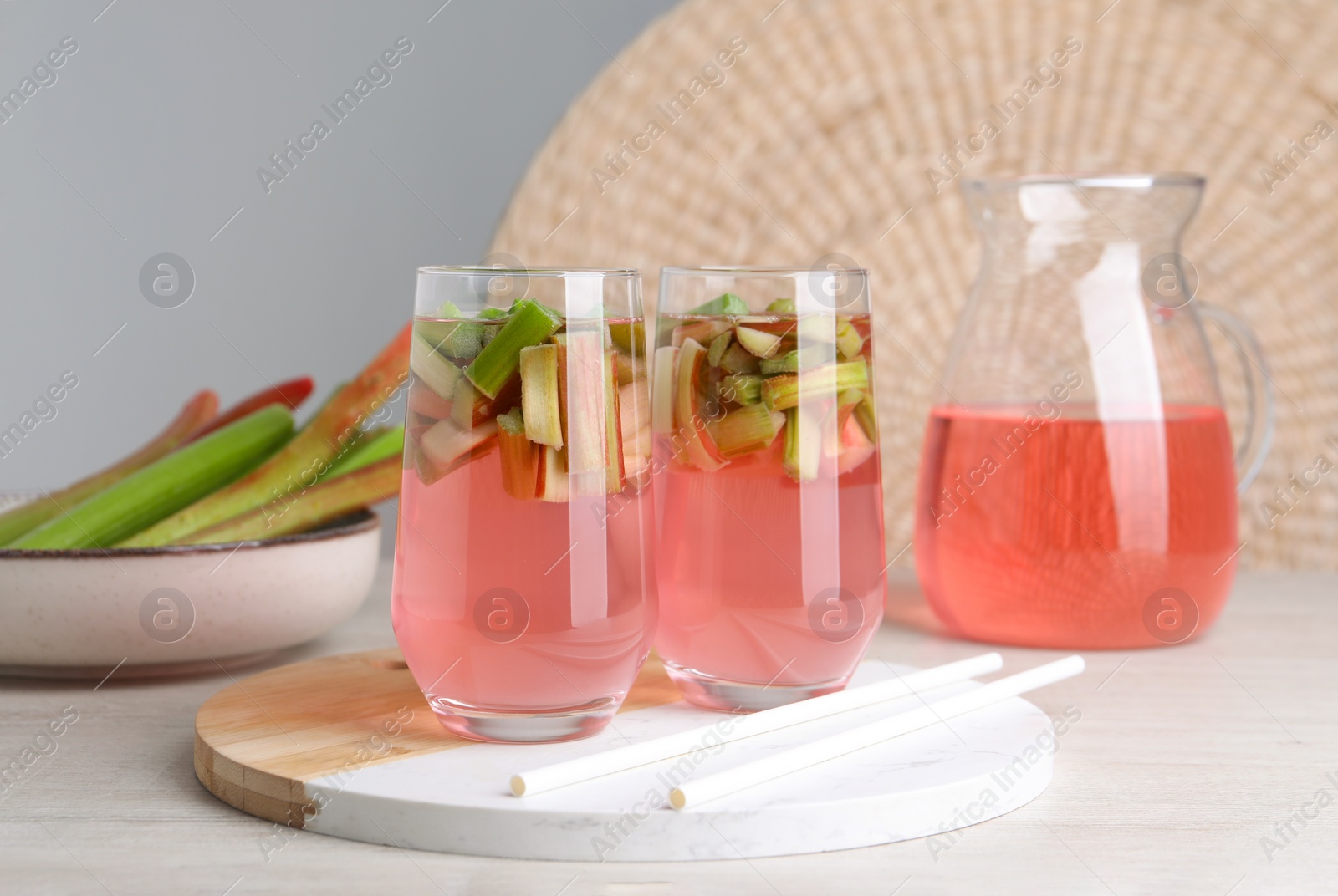 Photo of Glasses and jug of tasty rhubarb cocktail on white wooden table