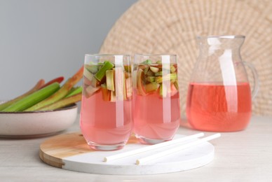 Glasses and jug of tasty rhubarb cocktail on white wooden table