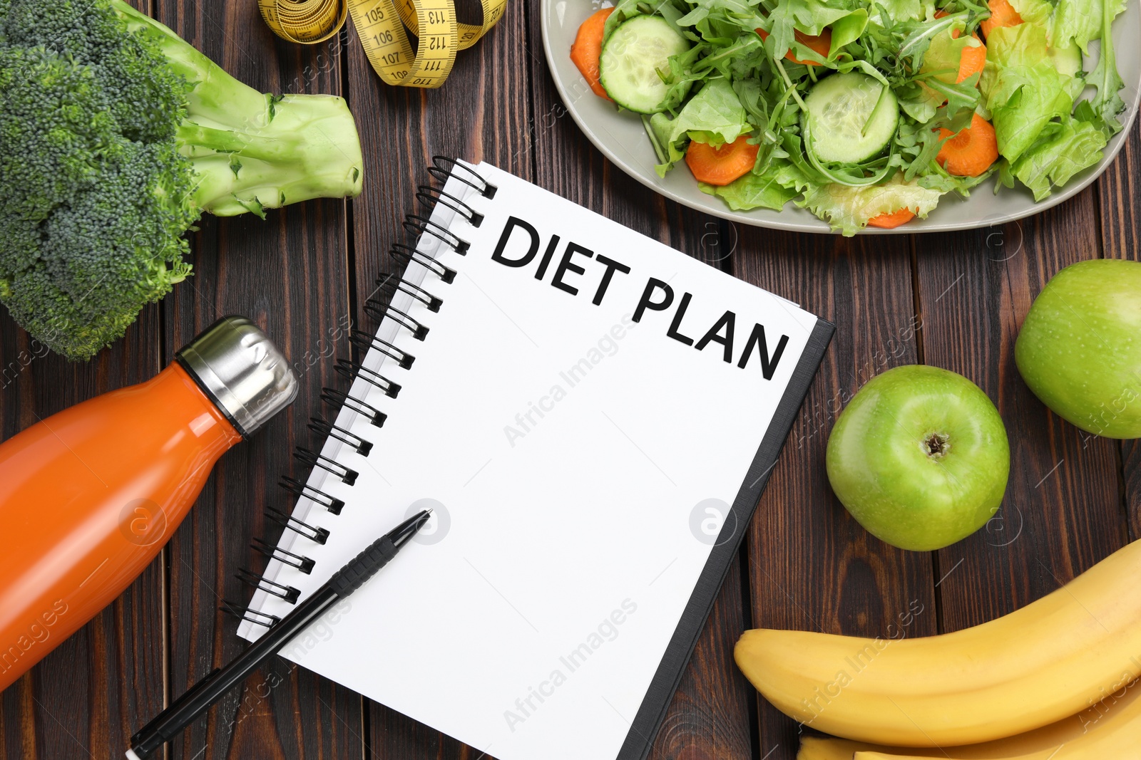 Photo of Notebook with phrase Diet Plan, bottle and different products on wooden table, flat lay. Weight loss concept