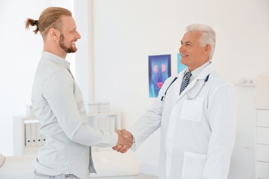 Urologist and thankful patient shaking hands at hospital