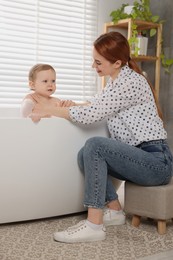 Mother washing her little baby in tub at home