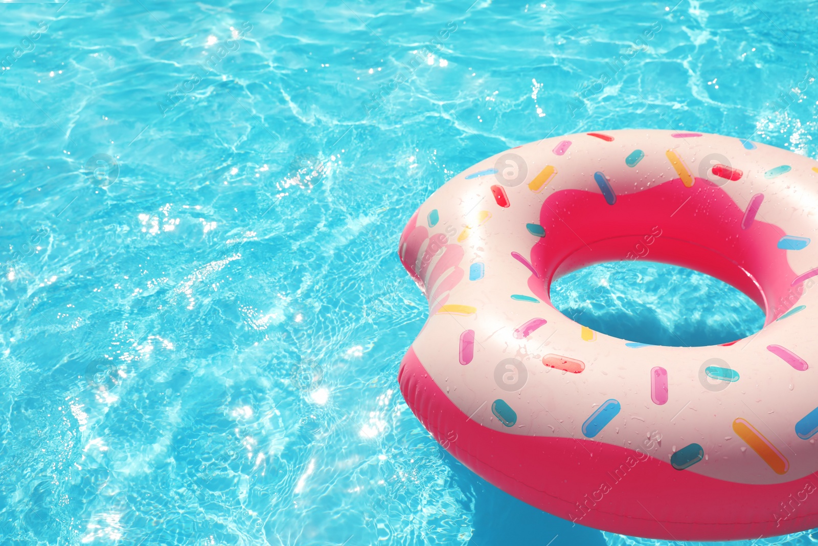 Photo of Inflatable ring floating in swimming pool on sunny day. Space for text