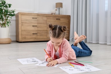 Photo of Cute little girl coloring on warm floor at home. Heating system