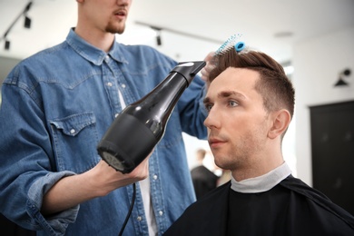 Photo of Professional barber working with client in hairdressing salon. Hipster fashion