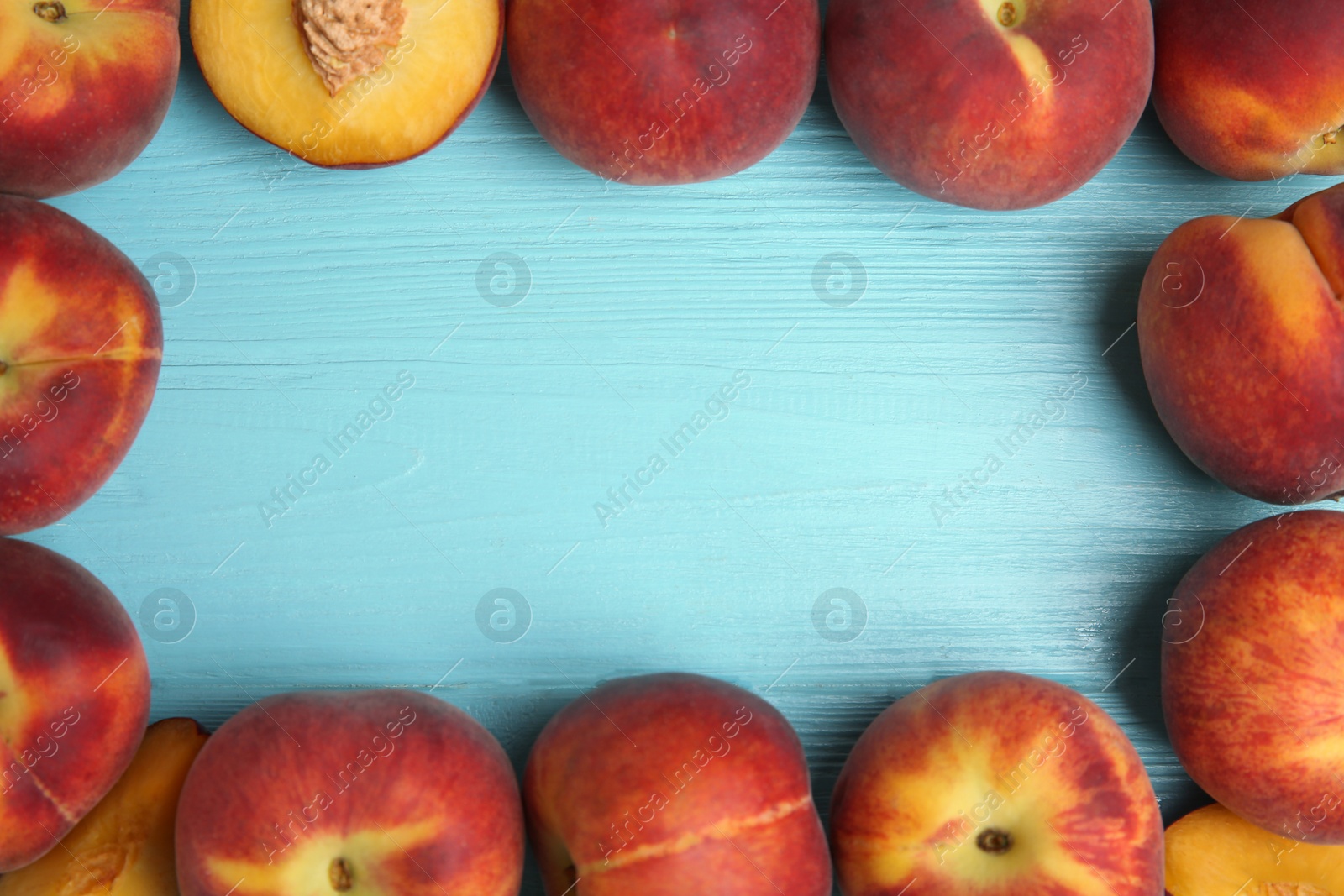 Photo of Frame made of fresh peaches on blue wooden table, top view with space for text