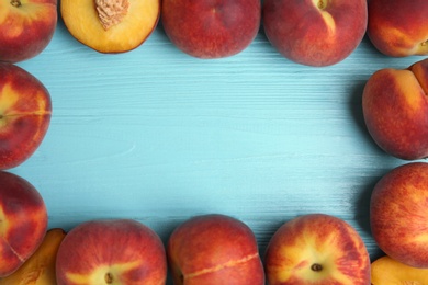 Frame made of fresh peaches on blue wooden table, top view with space for text