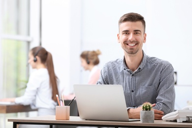 Photo of Male receptionist with laptop at desk in office