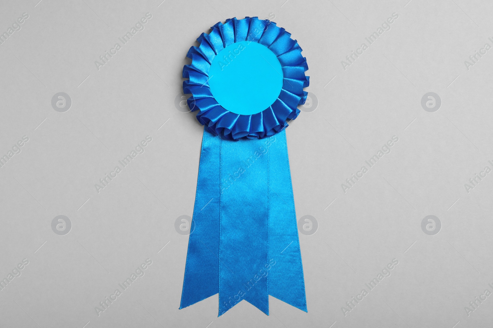 Photo of Blue award ribbon on grey background, top view