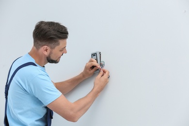 Male technician installing alarm system indoors