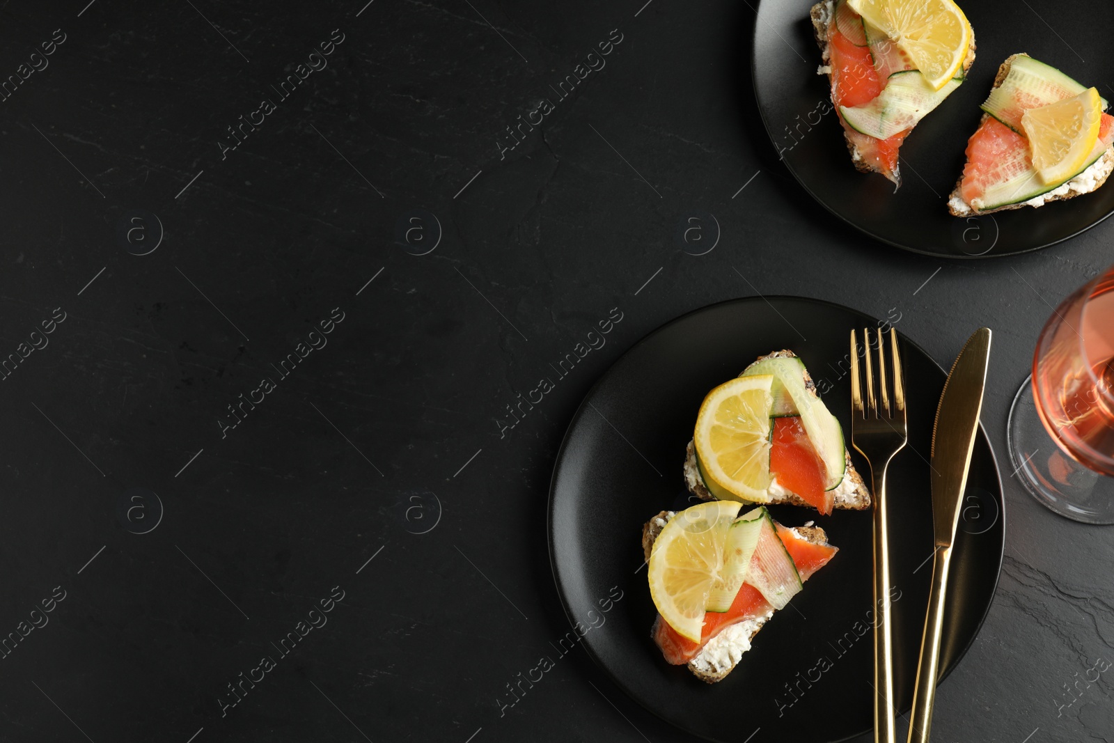 Photo of Flat lay composition with delicious bruschettas with salmon on black table, space for text