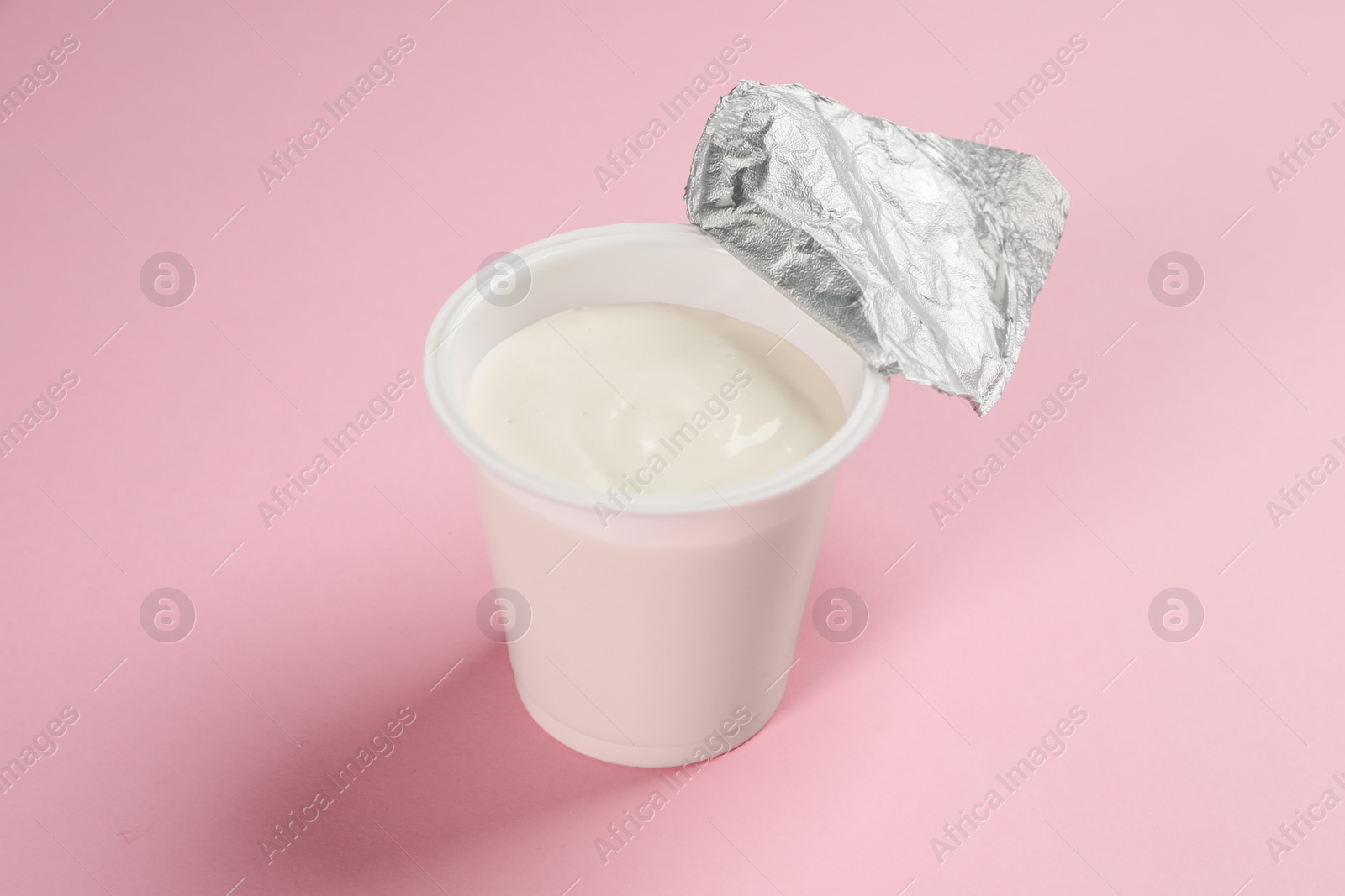 Photo of Plastic cup with tasty yogurt on pink background