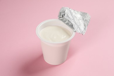 Photo of Plastic cup with tasty yogurt on pink background