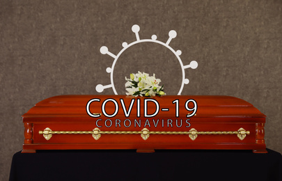 Coronavirus deaths. Funeral casket with white lilies at grey wall