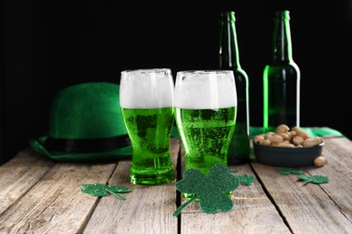 Photo of St. Patrick's day party. Green beer, decorative clover leaves, leprechaun hat and nuts on wooden table