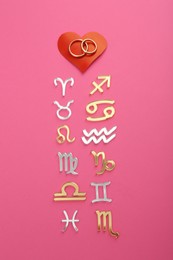 Zodiac compatibility. Signs, wedding rings and red heart on pink background, flat lay