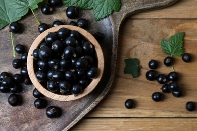 Ripe blackcurrants and leaves on wooden table, flat lay