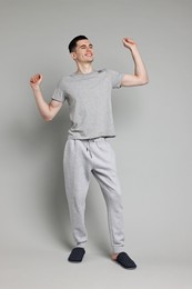 Photo of Happy man in pyjama stretching on grey background