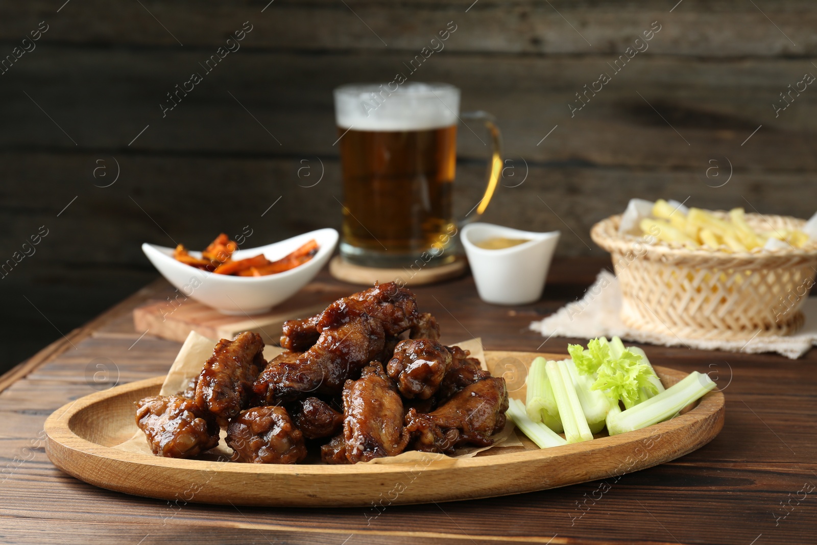 Photo of Delicious chicken wings served with beer on wooden table