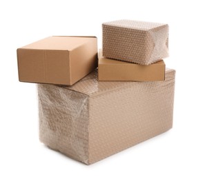 Photo of Cardboard boxes packed in bubble wrap and ordinary ones on white background