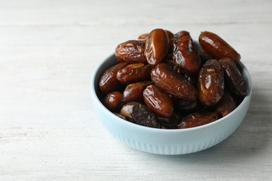 Bowl with sweet dates on wooden background, space for text. Dried fruit as healthy snack