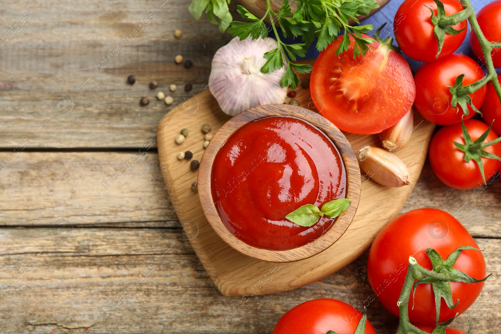 Photo of Tasty ketchup, fresh tomatoes, parsley and spices on wooden table, flat lay. Space for text