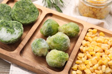 Tray with different frozen vegetables on wooden table, closeup