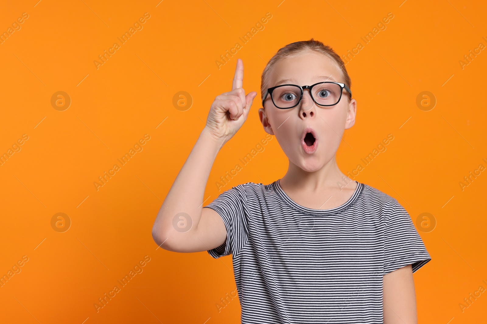 Photo of Portrait of emotional girl in glasses on orange background. Space for text