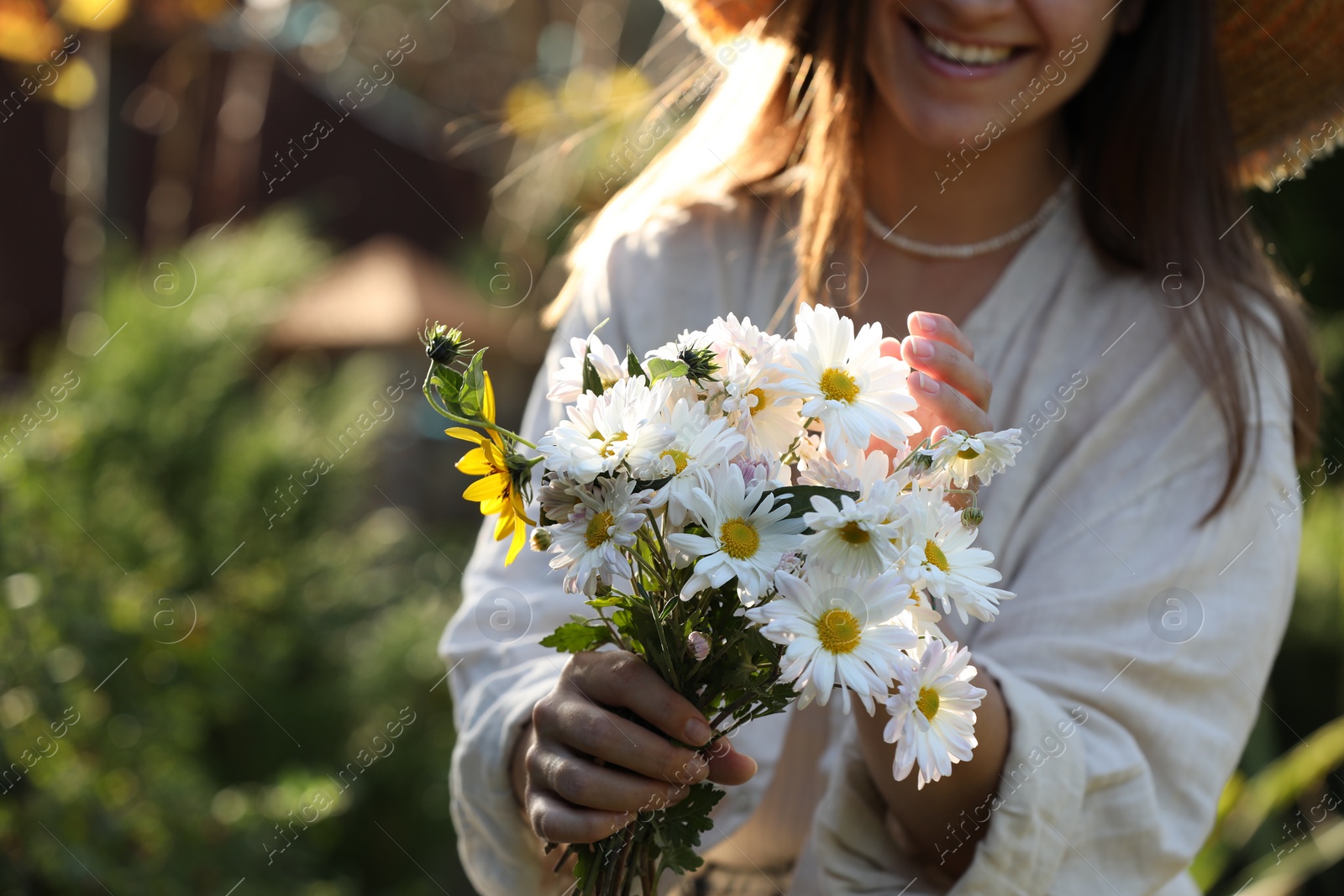 Photo of Woman holding bouquet of beautiful white chamomile flowers outdoors, closeup. Space for text