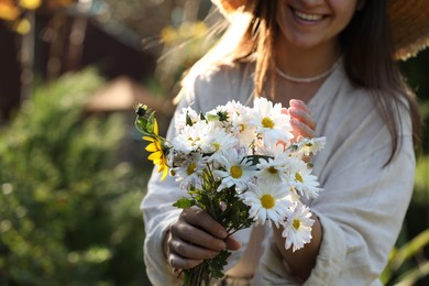 Photo of Woman holding bouquet of beautiful white chamomile flowers outdoors, closeup. Space for text