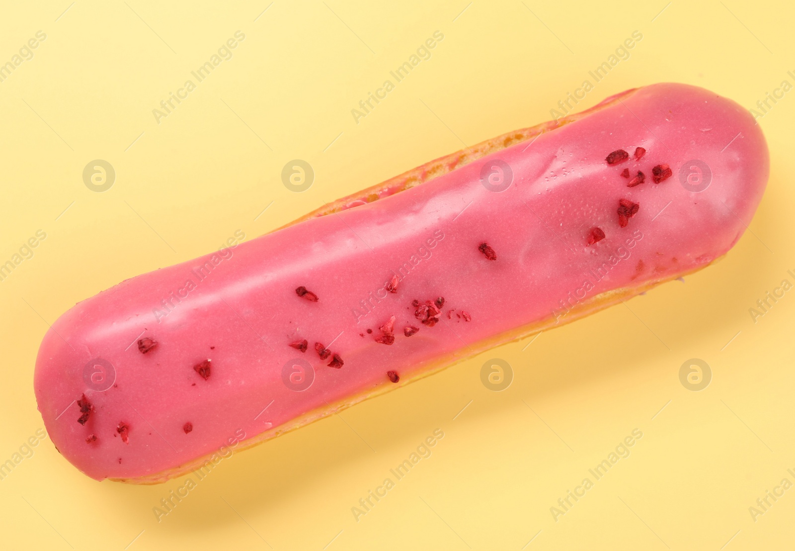 Photo of Delicious eclair covered with glaze on yellow background, top view