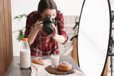 Young woman with professional camera taking food photo in studio