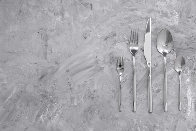Photo of Beautiful cutlery set on grey table, flat lay. Space for text