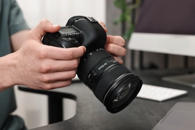 Photo of Photographer holding camera at dark table, closeup