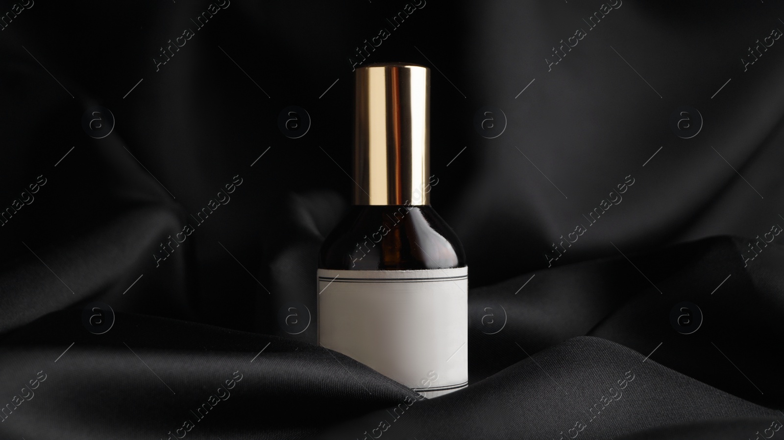 Photo of Luxury bottle of perfume on black silk