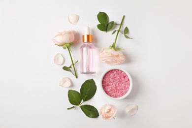 Photo of Composition with rose essential oil on white background, top view