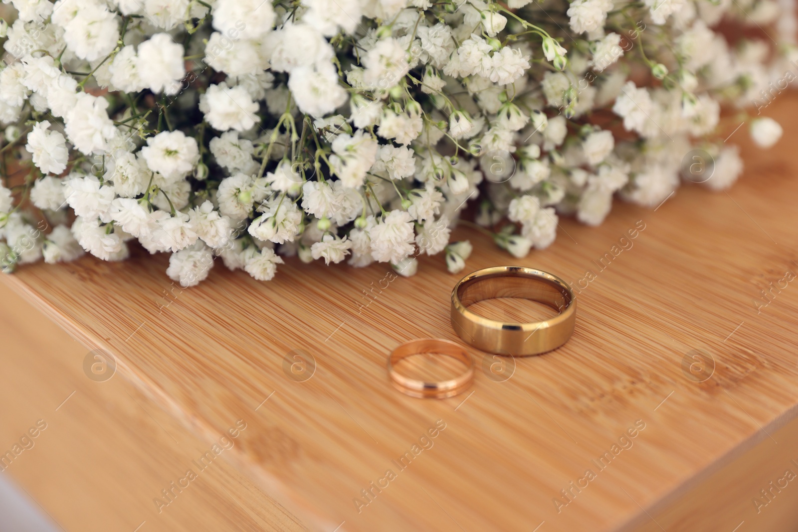 Photo of Engagement rings and beautiful bouquet on wooden table. Wedding day