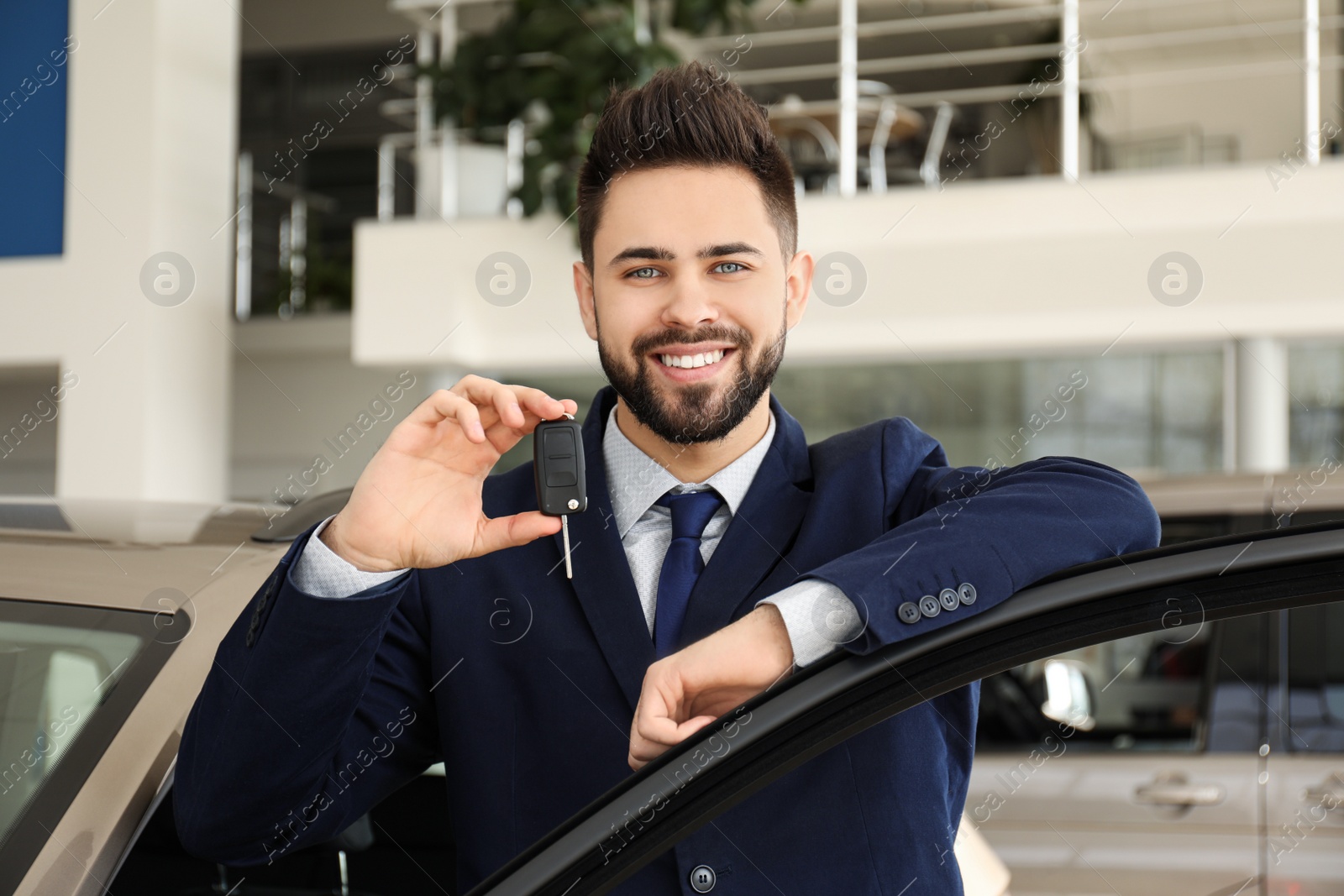 Photo of Salesman with key near car in dealership