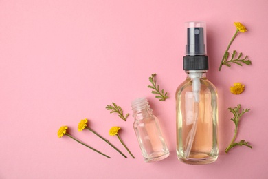 Photo of Bottles of essential oils and flowers on color background, flat lay. Space for text