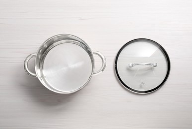 Empty steel pot and lid on white wooden table, flat lay