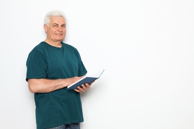 Photo of Senior man reading book on white background, space for text