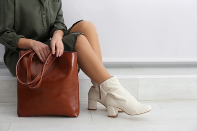 Woman wearing stylish leather shoes with bag indoors, closeup. Space for text