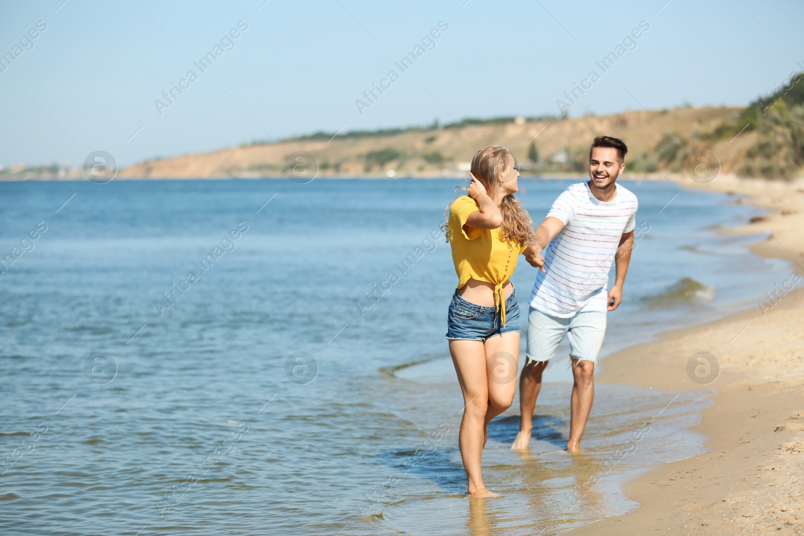 Photo of Happy young couple walking at beach on sunny day