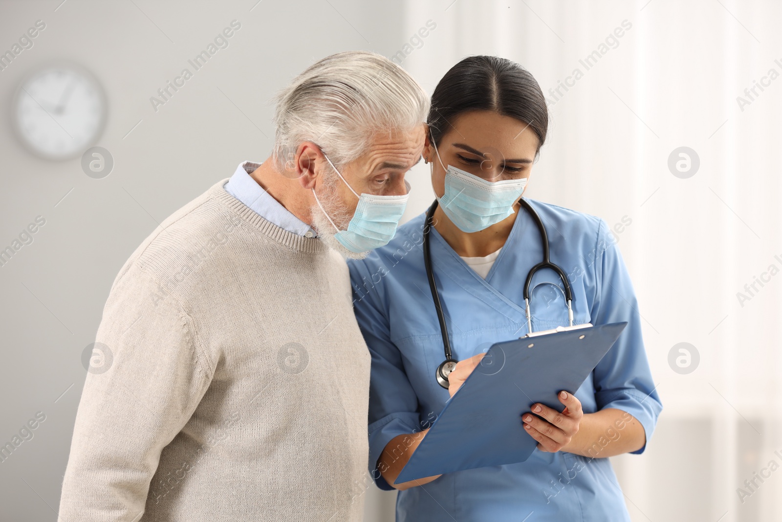 Photo of Nurse with clipboard and elderly patient in hospital