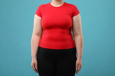 Photo of Overweight woman on light blue background, closeup