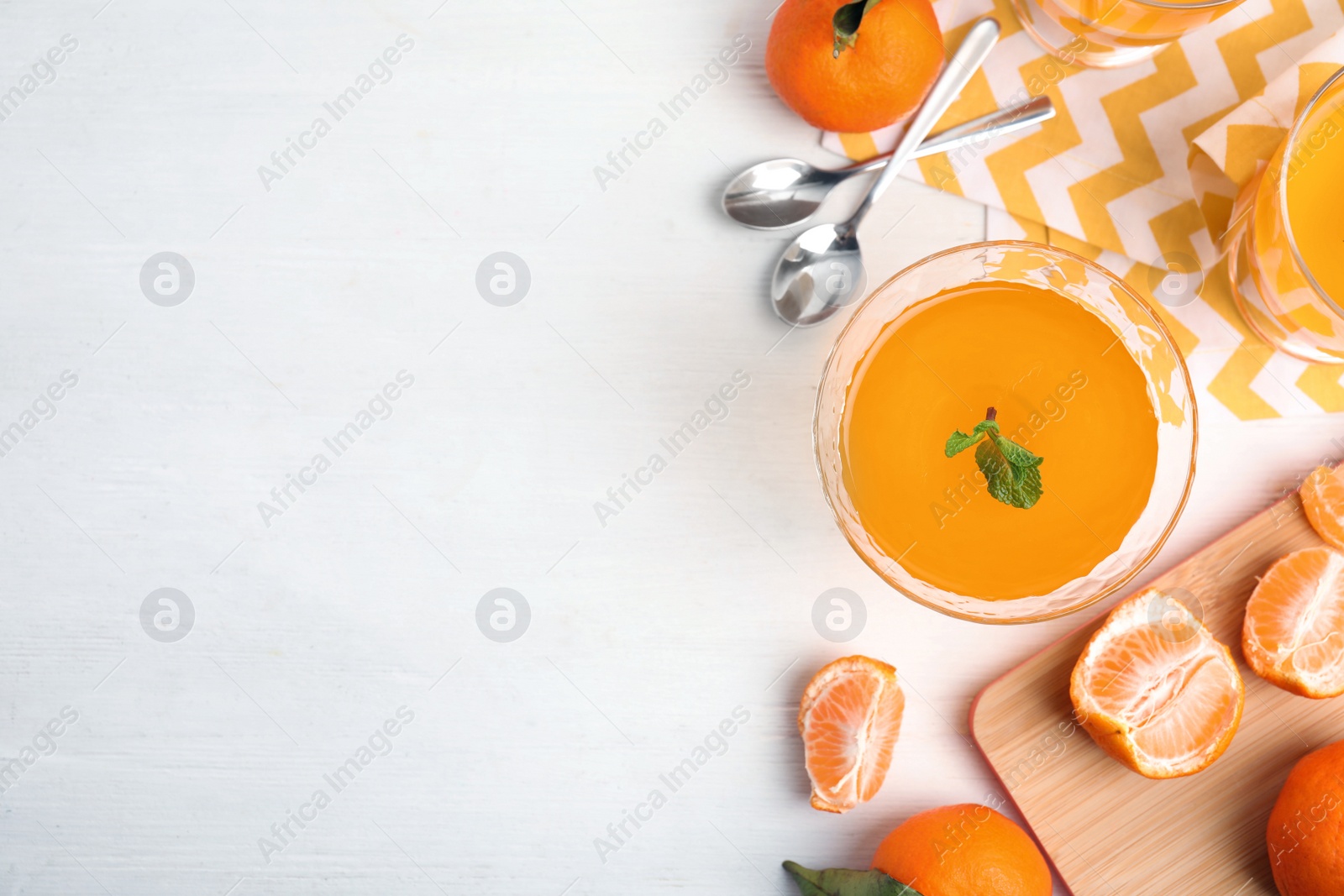 Photo of Delicious tangerine jelly and fresh fruits on white wooden table, flat lay. Space for text